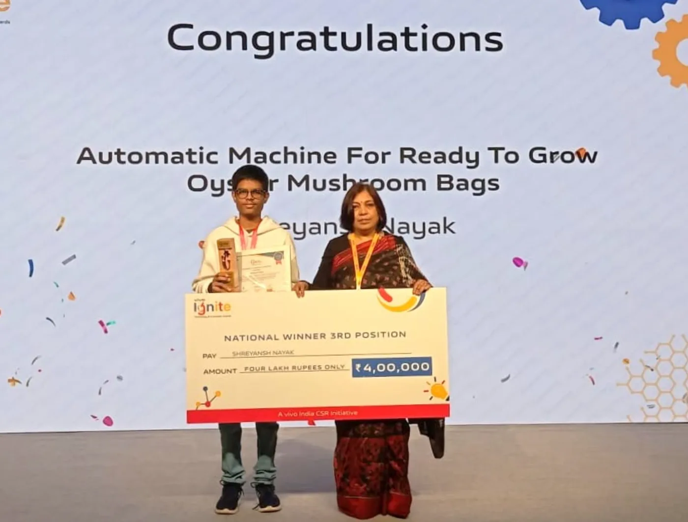 Shreyansh Nayak and an adult stand on stage with the Vivo Ignite third-place award